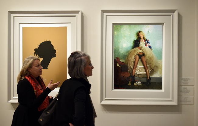 LONDON, ENGLAND - FEBRUARY 10:  Woman walk by framed photos at the press preview for 'Vogue 100: A Century of Style' exhibiting the photographs that has been commissioned by British Vogue since it was founded in 1916 at National Portrait Gallery on February 10, 2016 in London, England.  (Photo by Stuart C. Wilson/Getty Images)